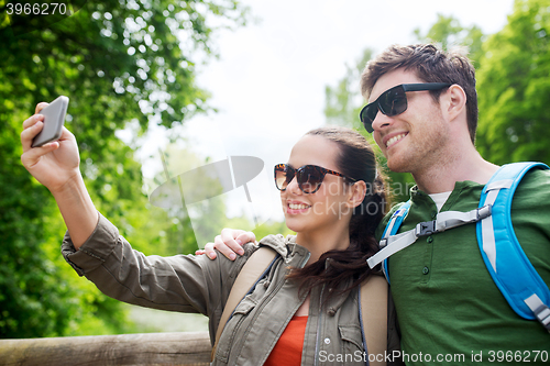 Image of couple with backpacks taking selfie by smartphone