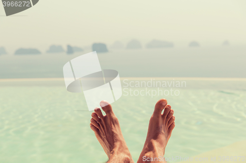 Image of closeup of male feet over sea and sky on beach