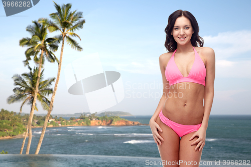 Image of happy young woman in pink bikini swimsuit on beach