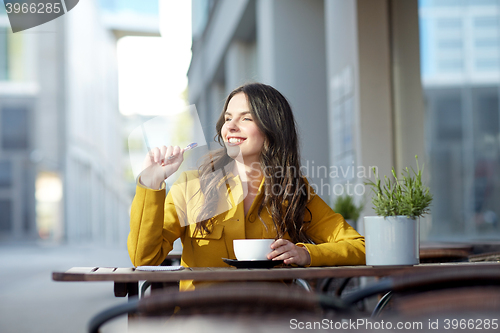 Image of happy woman with notebook drinking cocoa at cafe