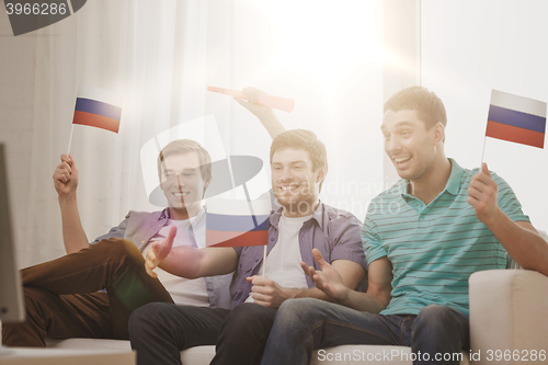 Image of happy male friends with flags and vuvuzela