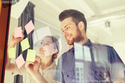 Image of happy creative team writing on stickers at office