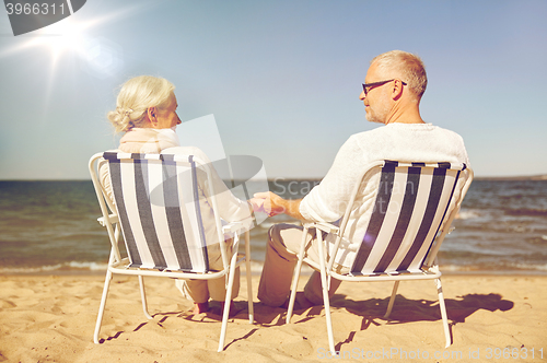 Image of happy senior couple in chairs on summer beach