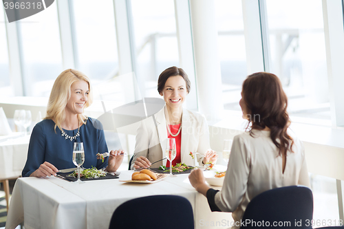 Image of happy women eating and talking at restaurant