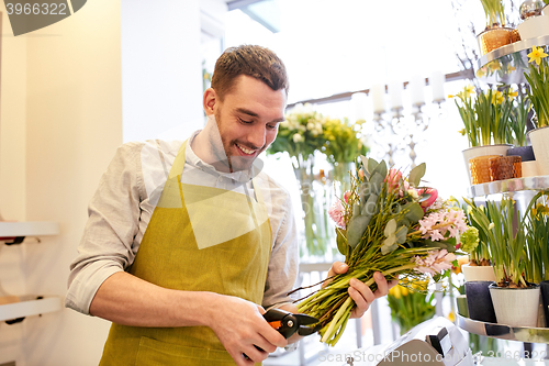 Image of smiling florist man making bunch at flower shop