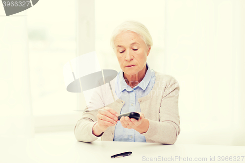 Image of senior woman with glucometer checking blood sugar