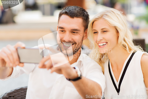 Image of happy couple taking selfie with smartphone at cafe