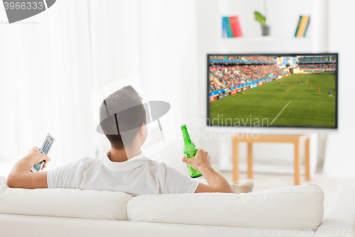 Image of man watching soccer game on tv and drinking beer