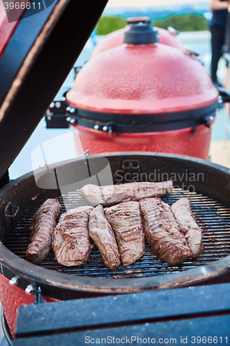 Image of thick strip steak being grilled outdoors. Shallow dof