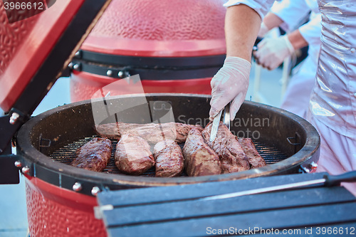 Image of thick strip steak being grilled outdoors. Shallow dof