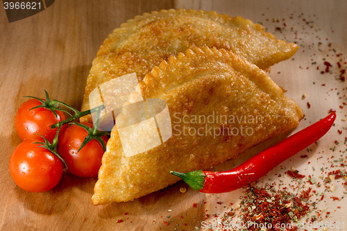Image of Caucasian cuisine. Cheburek pie on the wood background