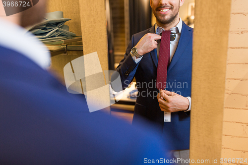 Image of close up of man trying tie on at mirror