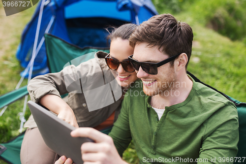 Image of happy couple with tablet pc at camping tent