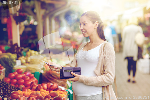 Image of pregnant woman with wallet buying food at market