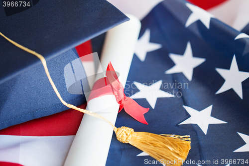 Image of bachelor hat and diploma on american flag