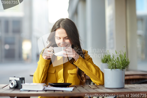 Image of happy tourist woman drinking cocoa at city cafe