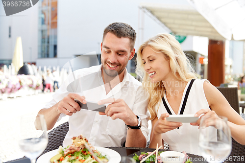 Image of happy couple with smatphone photographing food