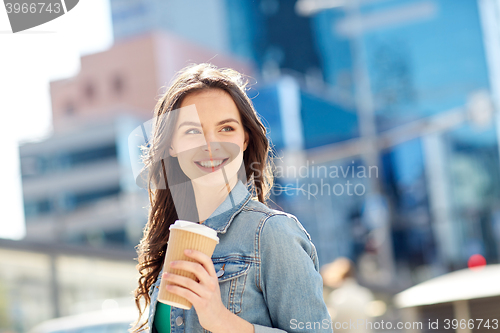 Image of happy young woman drinking coffee on city street