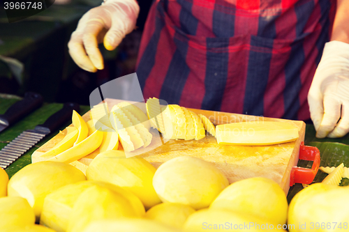 Image of close up of cook hands and mango at street market