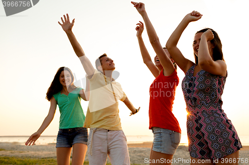 Image of smiling friends dancing on summer beach