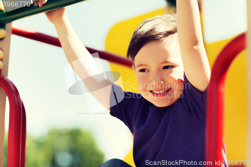 Image of happy little boy climbing on children playground