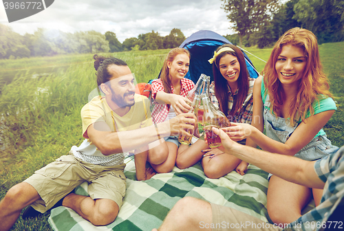 Image of happy friends with tent and drinks at campsite