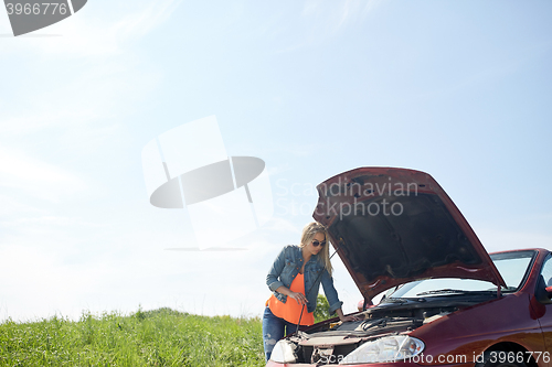 Image of woman with open hood of broken car at countryside
