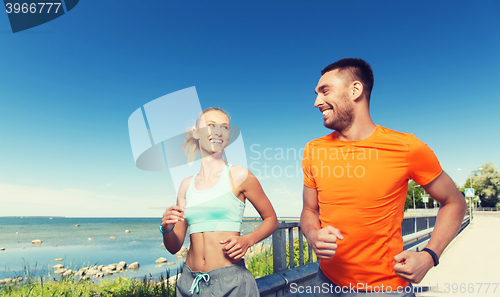 Image of smiling couple running at summer seaside