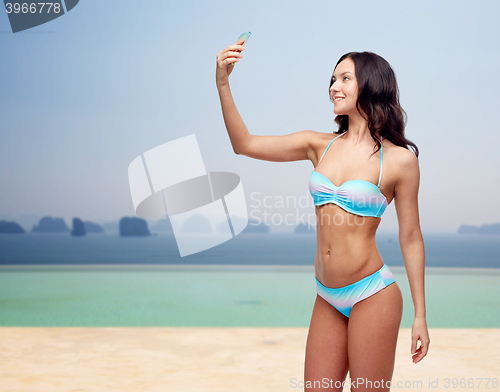 Image of woman in swimsuit taking selfie with smatphone