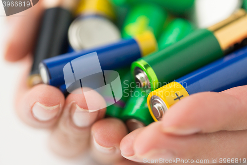 Image of close up of hands holding alkaline batteries heap