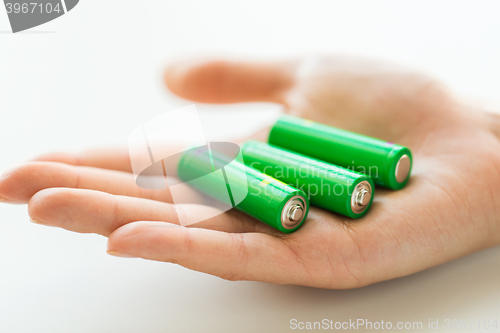 Image of close up of hand holding green alkaline batteries