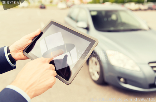 Image of close up of young man with tablet pc and car