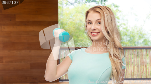 Image of smiling beautiful young sporty woman with dumbbell