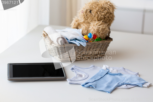 Image of close up of baby clothes, toys and tablet pc