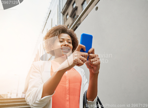 Image of happy african woman with smartphone in city