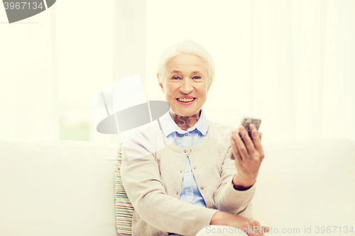 Image of senior woman with smartphone at home