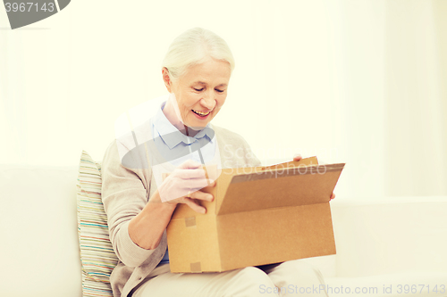 Image of happy senior woman with parcel box at home