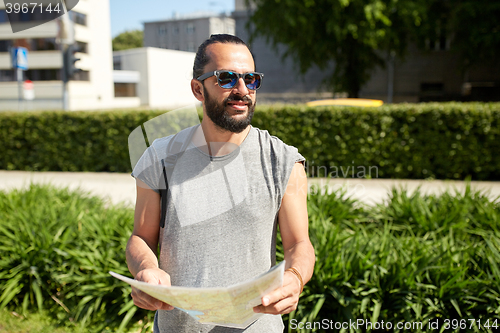 Image of man traveling with backpack and map in city