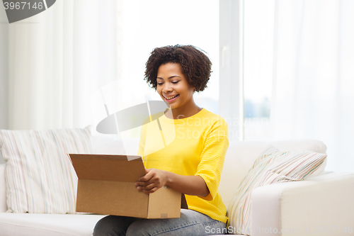 Image of happy african young woman with parcel box at home