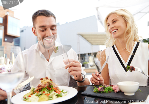 Image of happy couple eating dinner at restaurant terrace