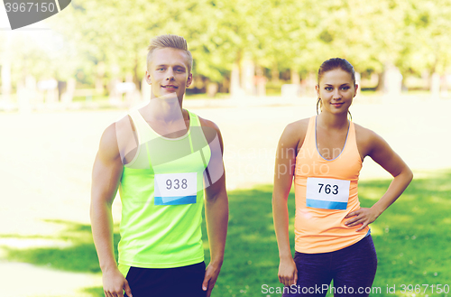 Image of happy friends or couple with racing badge numbers