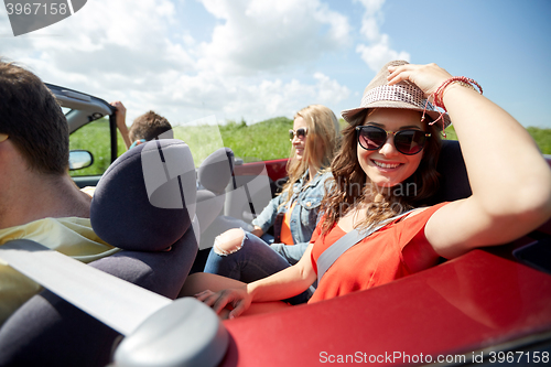 Image of happy friends driving in cabriolet car