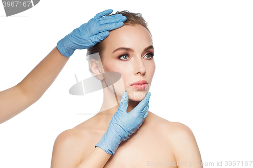 Image of surgeon or beautician hands touching woman face