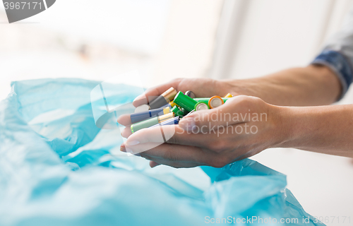 Image of close up of hands putting batteries to rubbish bag