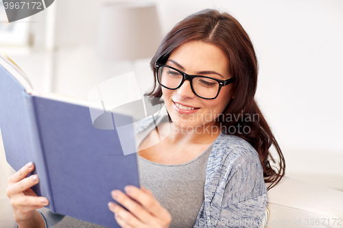 Image of happy pregnant woman reading book at home