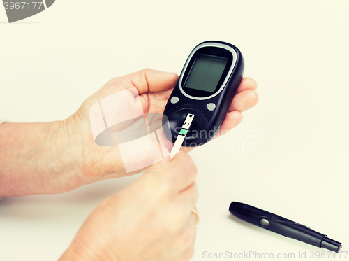 Image of senior woman with glucometer checking blood sugar