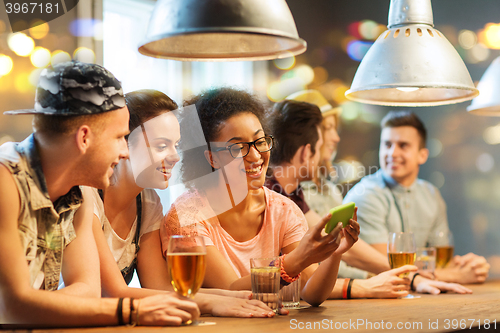 Image of happy friends with smartphone and drinks at bar