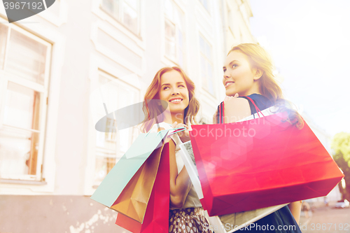 Image of happy women with shopping bags walking in city