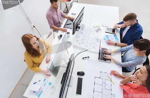 Image of creative team with computers, blueprint at office