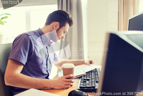 Image of creative male worker drinking coffee and reading